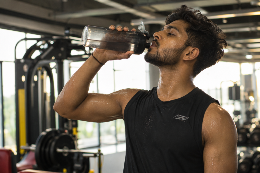 Staying hydrated while taking pre-workout in Indian gym.