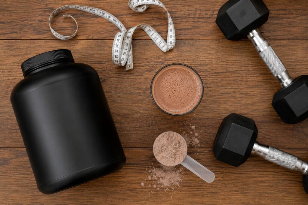 Mass gainer supplement tub with protein shake and dumbbells showing what mass gainer contains.